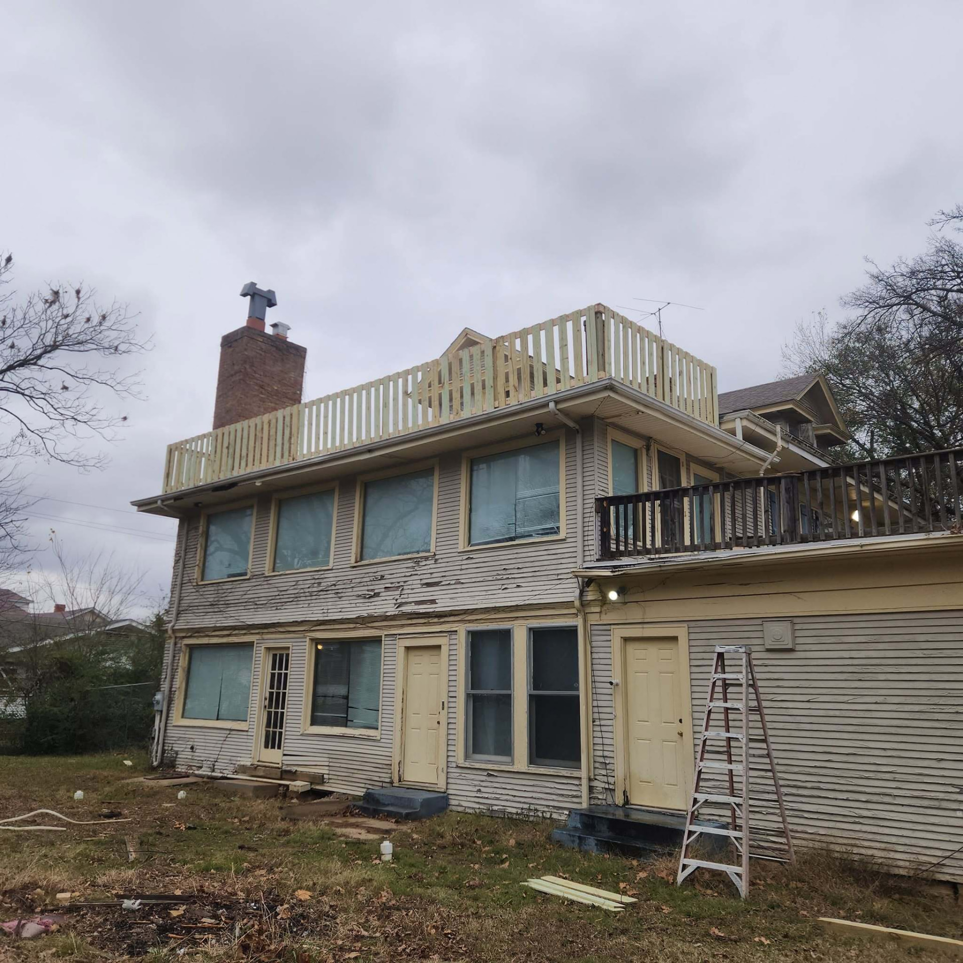 Exterior view of a two story home showing the completed light wood rooftop railing above the second floor